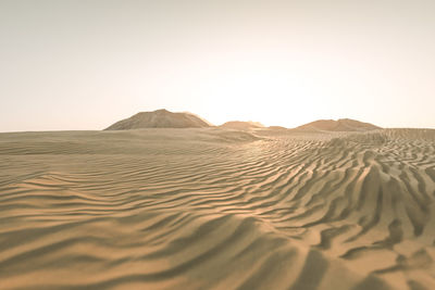 Sand dunes in desert against clear sky