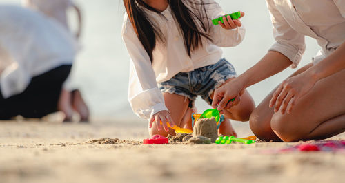 Low section of people making sandcastle at beach