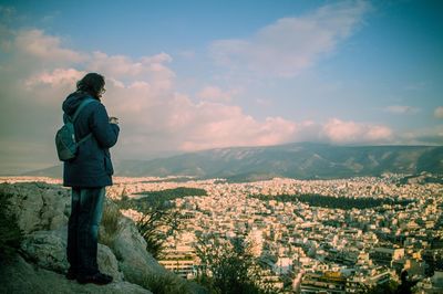 Man standing on rock against townscape