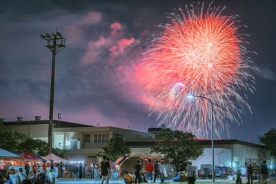 People watching fireworks against sky at night
