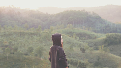 Rear view of woman standing against mountains during sunset