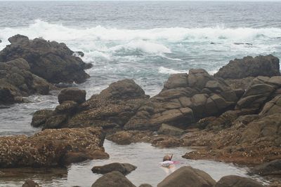 Woman swimming at beach amidst rocks