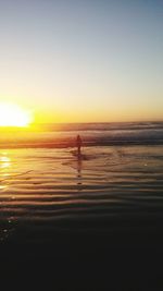 Silhouette person on beach against sky during sunset