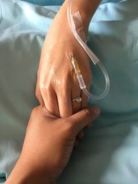 Cropped image of woman holding patient hand with iv drip in hospital