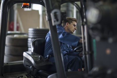 Factory working driving a fork lift in warehouse