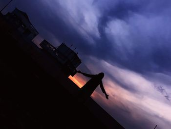 Low angle view of silhouette house against sky during sunset