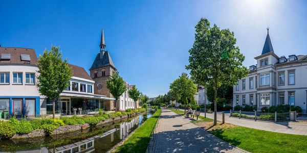 Panoramic view of trees and buildings against blue sky