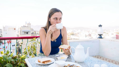 Woman looking away while drinking coffee at cafe