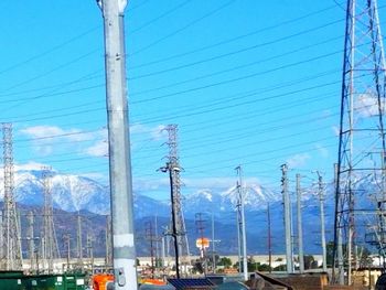 Electricity pylon in city against sky
