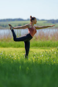 Full length of woman doing yoga on field