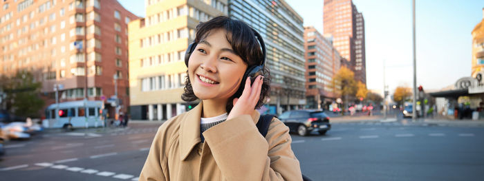 Side view of young woman standing in city