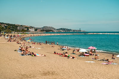 Group of people at beach against sky during summer