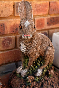 Rabbit sculpture by brick wall