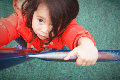 High angle view of cute girl holding metallic ladder at playground