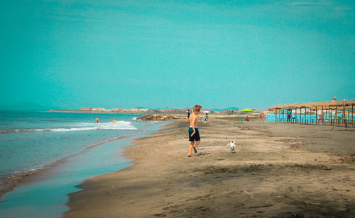 Full length of boy on beach against clear blue sky
