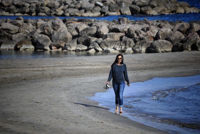 Full length of young woman at beach in front of rock