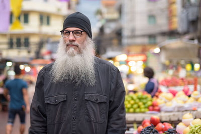 Portrait of man standing at market in city