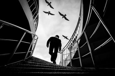 Low angle view of man flying by building against sky