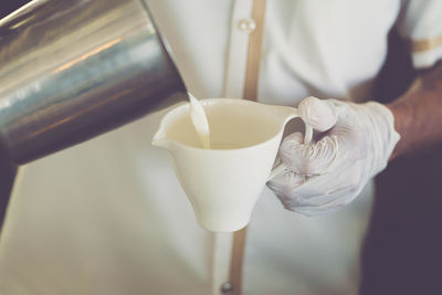 Close-up of hand pouring tea cup