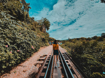 Rear view of woman standing on railroad track