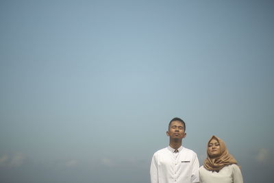 Portrait of a couple standing against clear sky