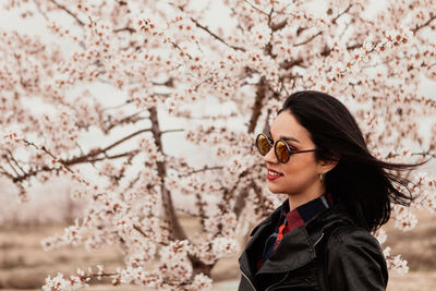 Low angle view of young woman with cherry blossom