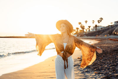 Rear view of woman standing at beach against clear sky