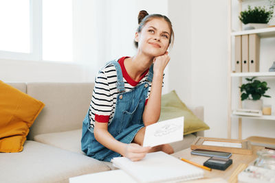 Portrait of woman using digital tablet while sitting on bed at home