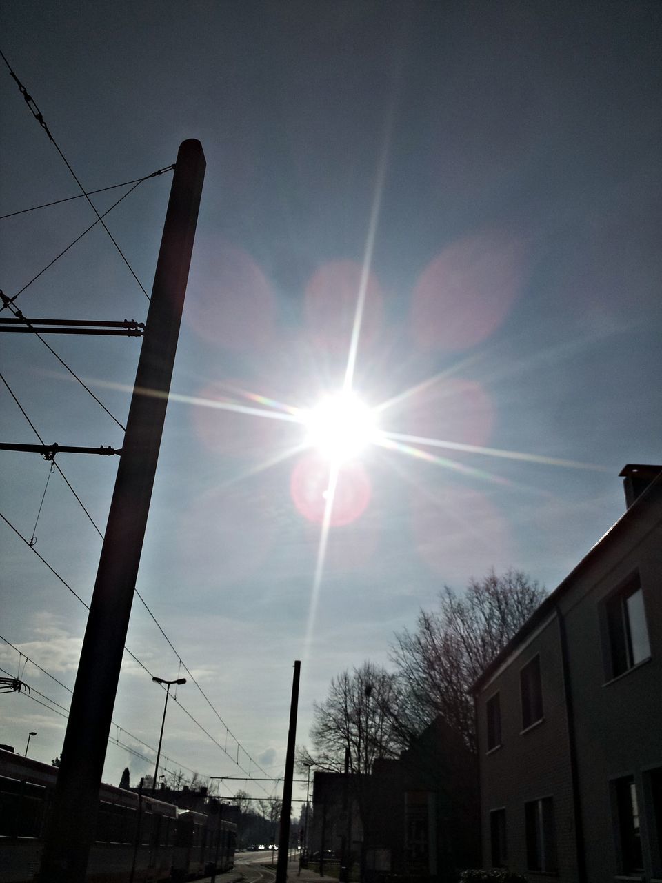 sun, built structure, building exterior, architecture, sunbeam, low angle view, sunlight, lens flare, sky, power line, bright, sunny, building, city, day, house, electricity pylon, outdoors, cable, residential building