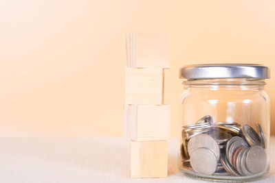 Close-up of glass jar on table against wall