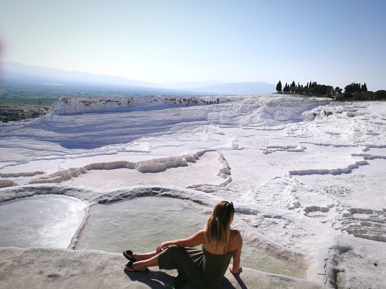 real people, one person, leisure activity, nature, beauty in nature, lifestyles, day, tranquil scene, outdoors, scenics, young women, tranquility, water, young adult, vacations, full length, women, sitting, sky, mountain, clear sky, people