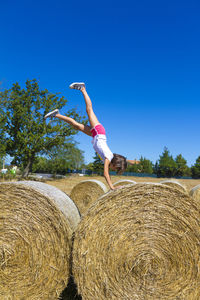 Woman with arms raised on field against sky