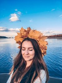 Beautiful woman wearing wreath in sea against sky