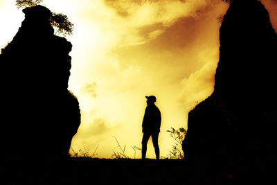 Silhouette man standing on field against sky during sunset