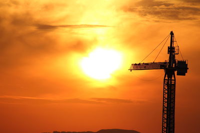 Low angle view of silhouette crane against sky during sunset