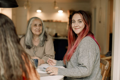 Portrait of smiling woman with mother and daughter sitting at home