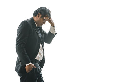 Side view of young man standing against white background