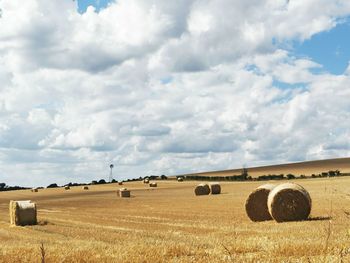 Hay bales on field against sky