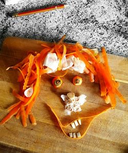 High angle view of anthropomorphic face made from carrot peel and garlic on cutting board