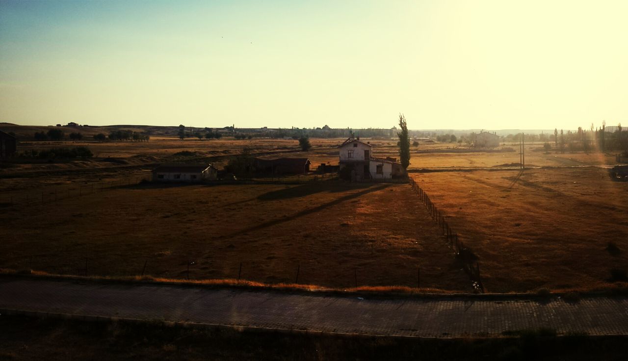 clear sky, copy space, landscape, built structure, field, sky, architecture, building exterior, tranquility, nature, outdoors, tranquil scene, road, no people, day, sunlight, rural scene, transportation, dirt, horizon over land