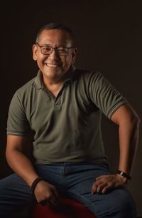 Portrait of a smiling young man sitting against black background