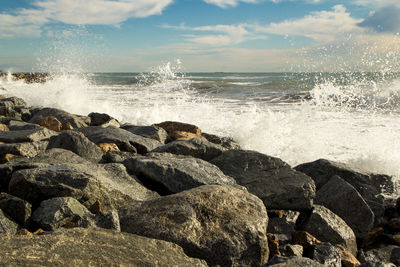 Scenic view of rocks in sea with waves splashing against