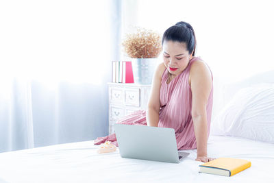 Young woman using mobile phone while sitting on table