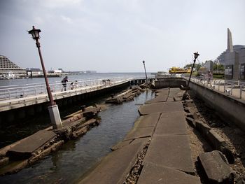 Pier on sea by city against sky