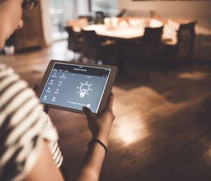 Woman using tablet with smart home control functions at home