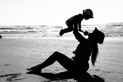 Silhouette men on beach against sky
