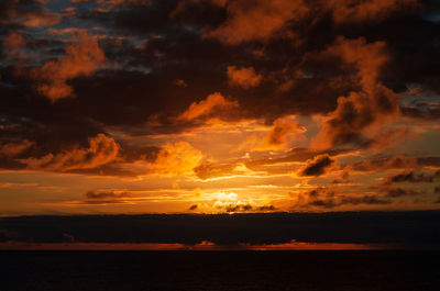 Scenic view of sea against dramatic sky during sunset