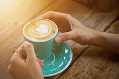 Midsection of woman holding coffee cup on table