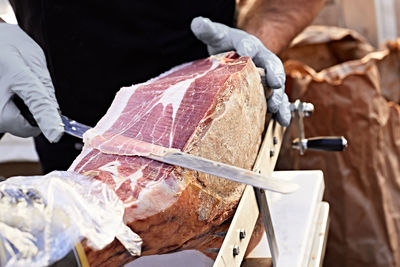 Midsection of man cutting raw meat with knife