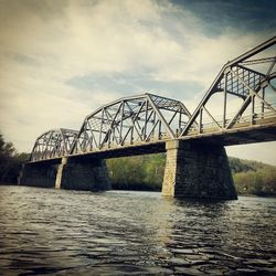 Bridge over river against cloudy sky